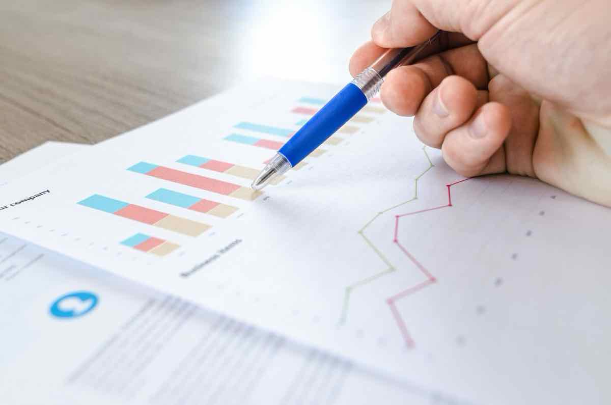 Hand holding a pen pointing at a printed bar chart