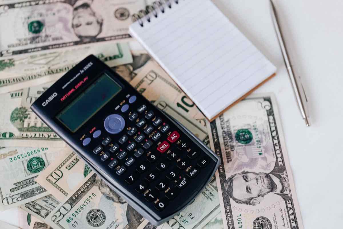 Calculator and notepad resting on top of dollar bills
