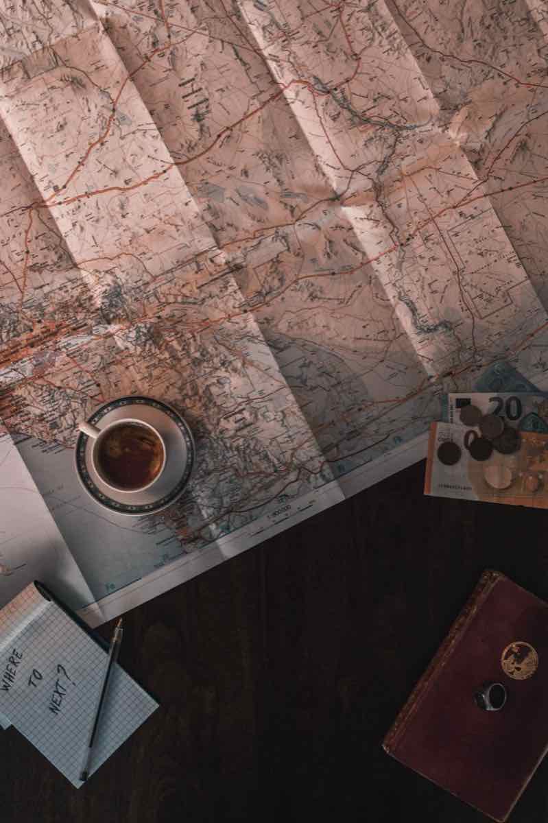 Paper road map on a table with a cup of coffee and a notebook