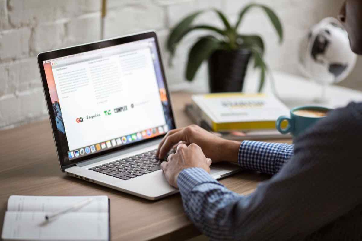Person browsing websites on a laptop at a bright desk